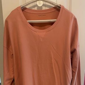 A beautiful peach colored Universal Standard open sided sweatshirt!